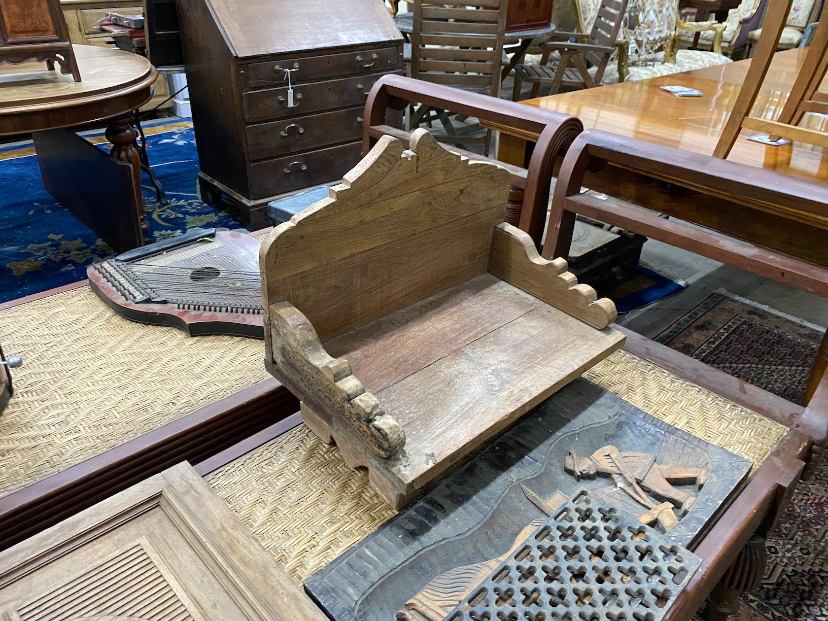 An Asian hardwood low seat, a relief carved panel, a lion's mask carved door and a cast iron grate